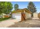 Side view of the residence with an attached white two-car garage and wooden fence at 2531 S Hoyt Ct, Lakewood, CO 80227