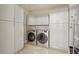Well-equipped laundry room featuring modern washer and dryer, upper and lower cabinets, tile floors and mosaic tile backsplash at 1827 N Grant St # 502, Denver, CO 80203
