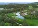 Scenic aerial view of a pristine golf course with lush green fairways, a tranquil pond, and surrounding trees at 4406 Orofino Pl, Castle Rock, CO 80108