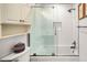 Bright bathroom features a tub with glass enclosure, neutral tiling, and built-in storage at 7255 W 97Th Pl, Broomfield, CO 80021