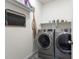 Well-equipped laundry room with modern washer and dryer, shelving, and decorative accents at 968 Honey Berry Ct, Elizabeth, CO 80107
