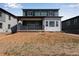Green two-story home featuring a cozy back porch and an unfinished backyard under a blue sky at 8581 Eckley St, Littleton, CO 80125