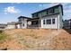 Green two-story home boasts a cozy back porch and an unfinished backyard under a sunny sky at 8581 Eckley St, Littleton, CO 80125