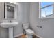 Bathroom with a pedestal sink, toilet, and window for natural light at 8581 Eckley St, Littleton, CO 80125