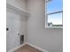 Small laundry room offers storage shelves, tile floors, and a bright window at 8581 Eckley St, Littleton, CO 80125
