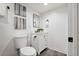 Well-lit powder bathroom with a toilet, sink, modern mirror, and decorative art at 1461 Hickory Ct, Erie, CO 80516