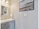 Small bathroom with gray vanity and white sink beneath an ornate painting and a light fixture at 1461 Hickory Ct, Erie, CO 80516
