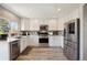 Bright kitchen featuring stainless steel appliances, white cabinets, and hardwood floors at 1461 Hickory Ct, Erie, CO 80516