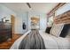 Well-lit main bedroom with hardwood floors, accent brick wall, and a doorway leading to the bathroom at 1461 Hickory Ct, Erie, CO 80516