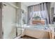Modern bathroom featuring a glass enclosed shower, soaking tub, and large window at 8208 Tabor Ct, Arvada, CO 80005