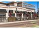 Exterior shot of a restaurant with outdoor seating under black awnings and red umbrellas at 2430 Ames St, Edgewater, CO 80214