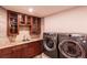 Laundry room with upper cabinets, modern washer and dryer, granite countertops, and tiled accents at 93 Glenmoor Dr, Englewood, CO 80113