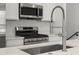 Close-up of modern kitchen island with sink and faucet, stainless range and microwave at 2046 S Holly St # 1, Denver, CO 80222