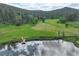 Scenic aerial view of a beautiful country estate with rolling hills, pond, dock and lush landscape at 31189 Manitoba Dr, Evergreen, CO 80439
