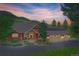Charming exterior of a home with a well-maintained yard, mature trees, and a three-car garage at 31189 Manitoba Dr, Evergreen, CO 80439