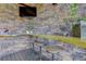 Inviting outdoor bar area features a stone accent wall, counter seating, and mounted TV for entertainment at 31189 Manitoba Dr, Evergreen, CO 80439