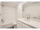 Modern bathroom featuring white tile, a shower and bath, a white vanity, chrome fixtures, and vinyl flooring at 1224 S Algonquian St, Aurora, CO 80018