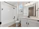 Bright bathroom features a shower-tub combo, white tile, and vanity with storage space and black hardware at 1300 Sienna Peak Cir, Erie, CO 80516