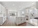 Open-concept kitchen with white cabinets, an island, quartz countertops, and wood laminate flooring at 1300 Sienna Peak Cir, Erie, CO 80516