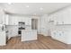 Modern kitchen with white cabinets, stainless steel appliances, quartz countertops, and wood laminate flooring at 1300 Sienna Peak Cir, Erie, CO 80516