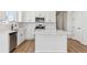 Modern kitchen with white cabinets, stainless steel appliances, quartz countertops, and wood laminate flooring at 1300 Sienna Peak Cir, Erie, CO 80516