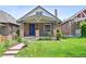 Charming brick home with a gabled roof, covered front porch, blue front door and well-manicured lawn at 3316 N Columbine St, Denver, CO 80205