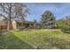 Expansive lawn with mature trees, a brick home, covered patio, and well-manicured landscape at 4114 S Niagara Way, Denver, CO 80237