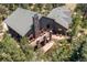 Aerial view showcases a home with an expansive deck, stone chimney, lush landscaping, and a picturesque pond at 8361 Piney Creek Rd, Parker, CO 80138