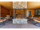 Covered outdoor area with a central stone fireplace, wood paneling, and cozy seating arrangements at 8361 Piney Creek Rd, Parker, CO 80138