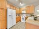 Well-lit kitchen featuring oak cabinetry, white appliances, and a corner sink at 16366 E Fremont Ave # 3, Aurora, CO 80016