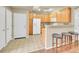 Spacious kitchen featuring oak cabinets, breakfast bar, and access to the front door at 16366 E Fremont Ave # 3, Aurora, CO 80016