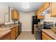 Bright kitchen with black appliances, wooden cabinets, and tile flooring at 7440 S Blackhawk St # 205, Englewood, CO 80112