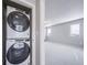 Convenient laundry area with a stacked washer and dryer, conveniently near a bedroom at 46566 Avery Ln, Bennett, CO 80102