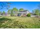 Large backyard with well-maintained lawn, patio, mature trees, and white fencing at 6800 Saddleback Ave, Firestone, CO 80504