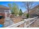 Fenced backyard with rock ground cover, walkway, mature trees, and dog door access at 6800 Saddleback Ave, Firestone, CO 80504