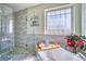 Bright bathroom with a modern glass-enclosed shower and a soaking tub beneath a window at 6800 Saddleback Ave, Firestone, CO 80504