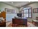 Bright home office with a large wooden desk, a patterned rug, and a beautiful arched window at 6800 Saddleback Ave, Firestone, CO 80504