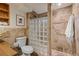 A bathroom featuring a tile shower with glass block, alongside a toilet, and wooden storage shelves at 977 S Reed St, Lakewood, CO 80226