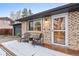 Inviting covered porch with seating, a glass storm door, and charming brick facade at 977 S Reed St, Lakewood, CO 80226
