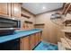 Large kitchen pantry with wall-mounted microwave, blue counter tops and wood cabinetry and shelving at 977 S Reed St, Lakewood, CO 80226