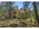 Charming exterior featuring a tall chimney, balcony, and natural landscape with mature trees at 474 Silbrico Way, Castle Rock, CO 80108