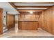 Basement entertaining area featuring a wooden bar, wall paneling, and tile flooring at 5285 E Iliff Ave, Denver, CO 80222
