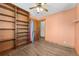 A cozy bedroom with hardwood floors, custom built-in bookshelf, and a ceiling fan at 5285 E Iliff Ave, Denver, CO 80222