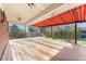 Spacious covered deck with wood flooring, awning, ceiling fans, string lights and views of fenced backyard at 5285 E Iliff Ave, Denver, CO 80222