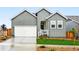 Charming two-story home boasts a light-gray exterior, a white garage door and manicured landscaping at 17125 W 92Nd Loop, Arvada, CO 80007