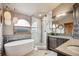 Spa-like bathroom with soaking tub, glass shower, natural stone accents, and mountain views at 3961 Mossy Rock Ln, Evergreen, CO 80439