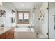 Relaxing bathroom featuring a soaking tub under a picture window and glass-enclosed shower at 3961 Mossy Rock Ln, Evergreen, CO 80439