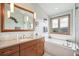 Bright bathroom with vanity, soaking tub under picture window, and updated shower at 3961 Mossy Rock Ln, Evergreen, CO 80439