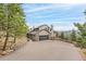 Stunning multi-story home with stone accents, a driveway, and mature trees against a beautiful sky at 3961 Mossy Rock Ln, Evergreen, CO 80439