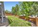 Fenced backyard with green lawn and stairs to the deck at 9921 W Edenburg Pl, Littleton, CO 80127